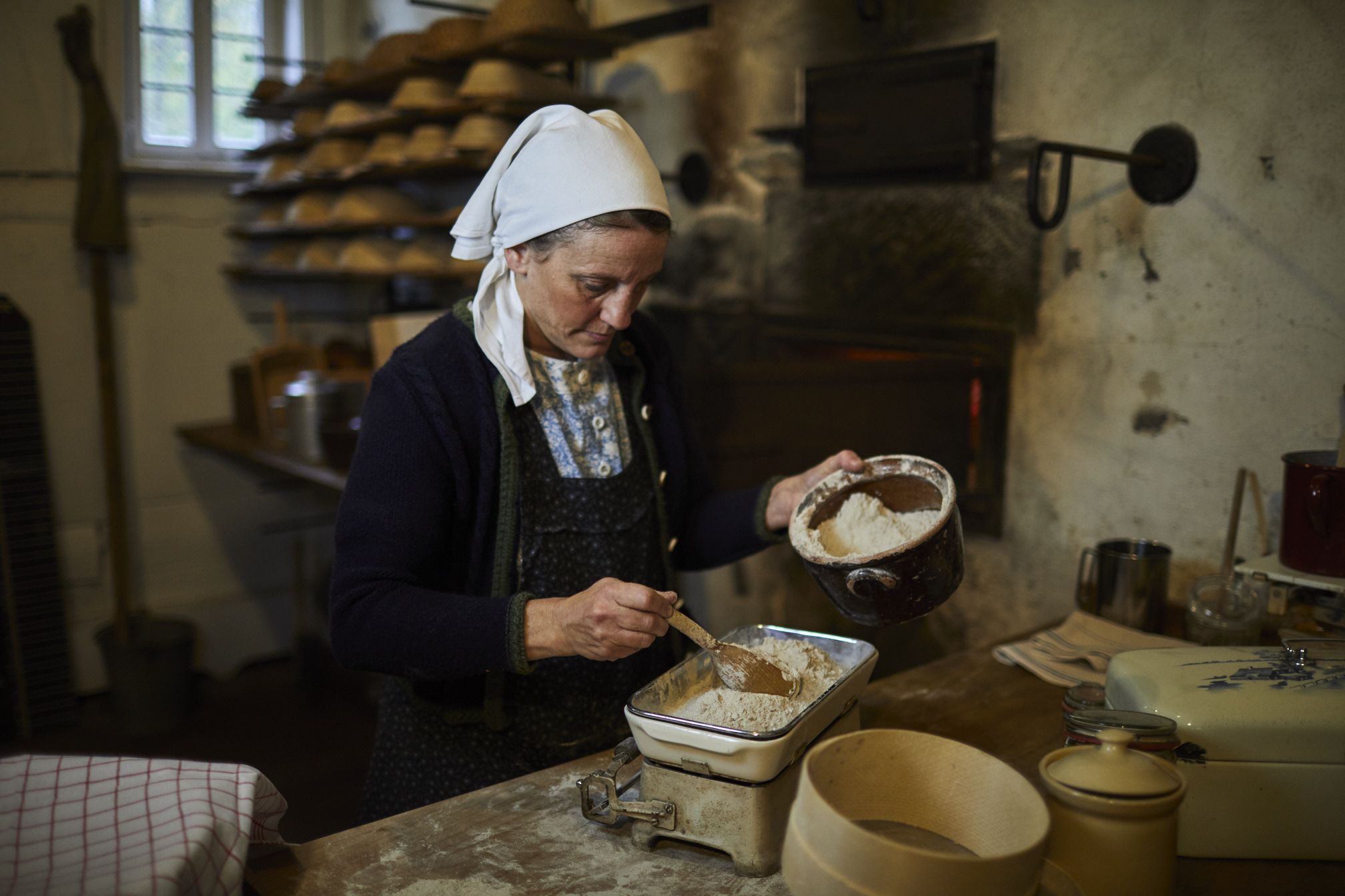 Bäckerin backt Brot im Backhaus