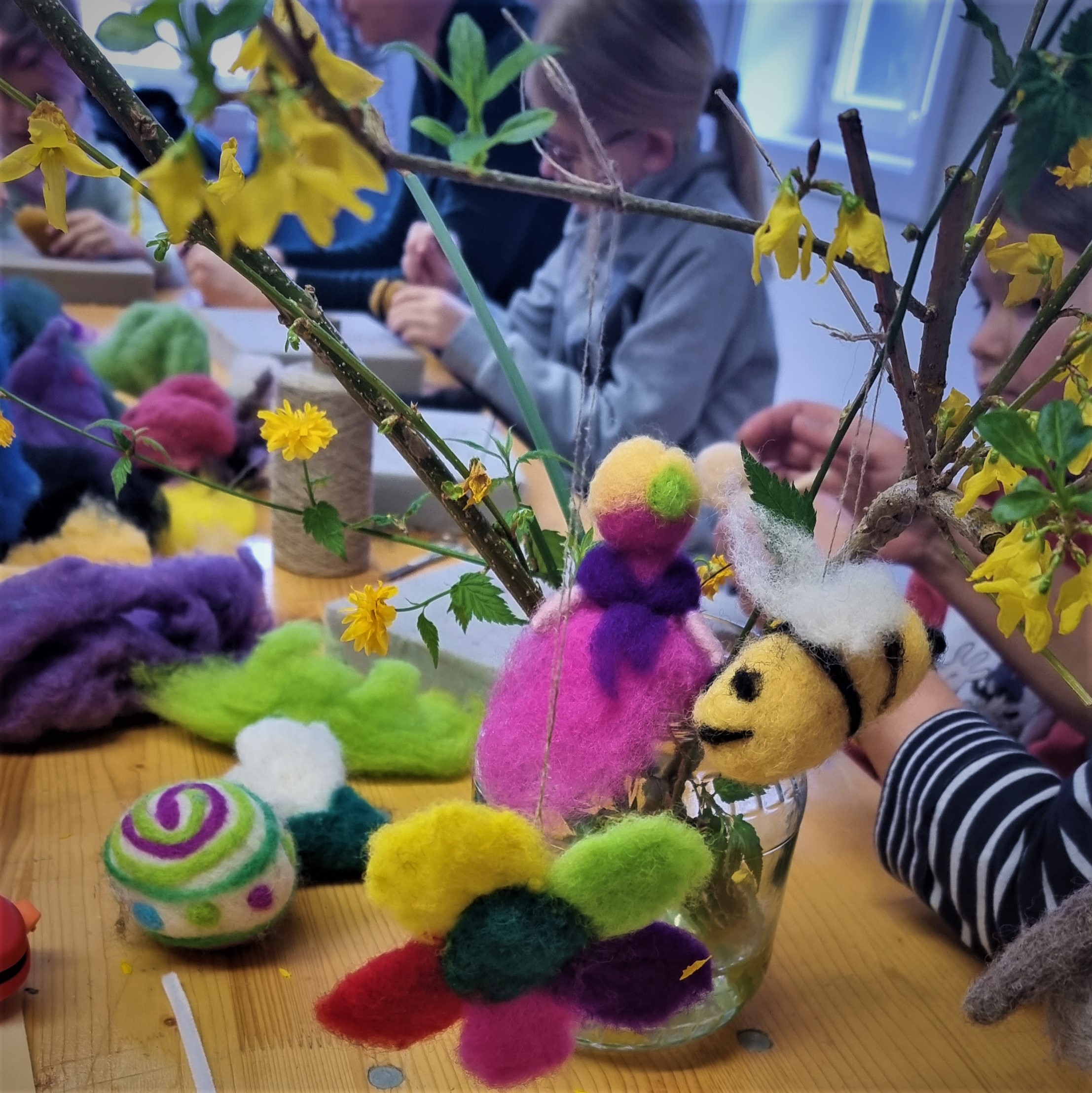 Kinder beim Filzen von frühlingshaften Motiven (Blume, Biene, Vogel)