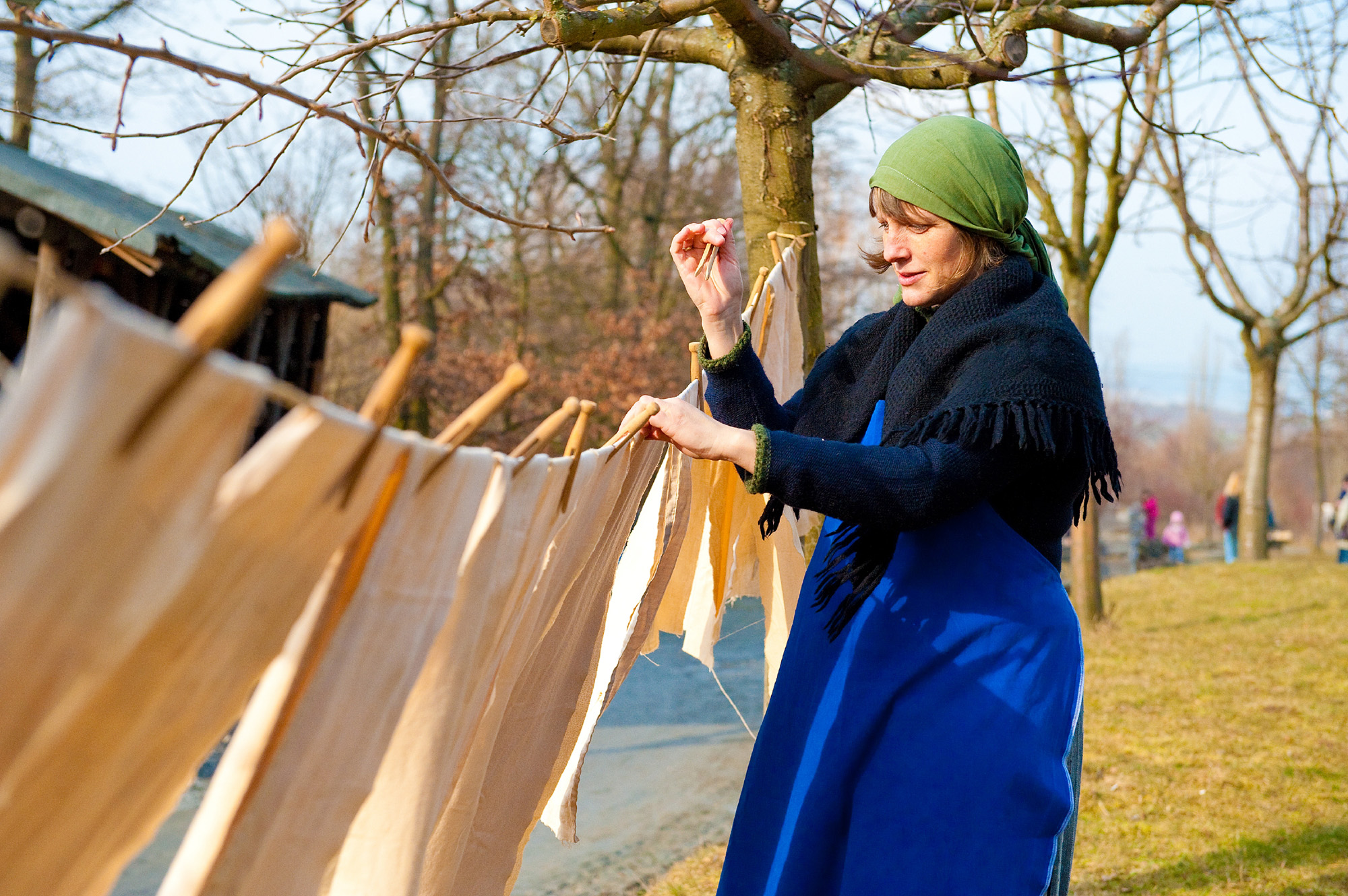 historische Hausfrau hängt im Winter Wäsche auf eine Leine im Freien