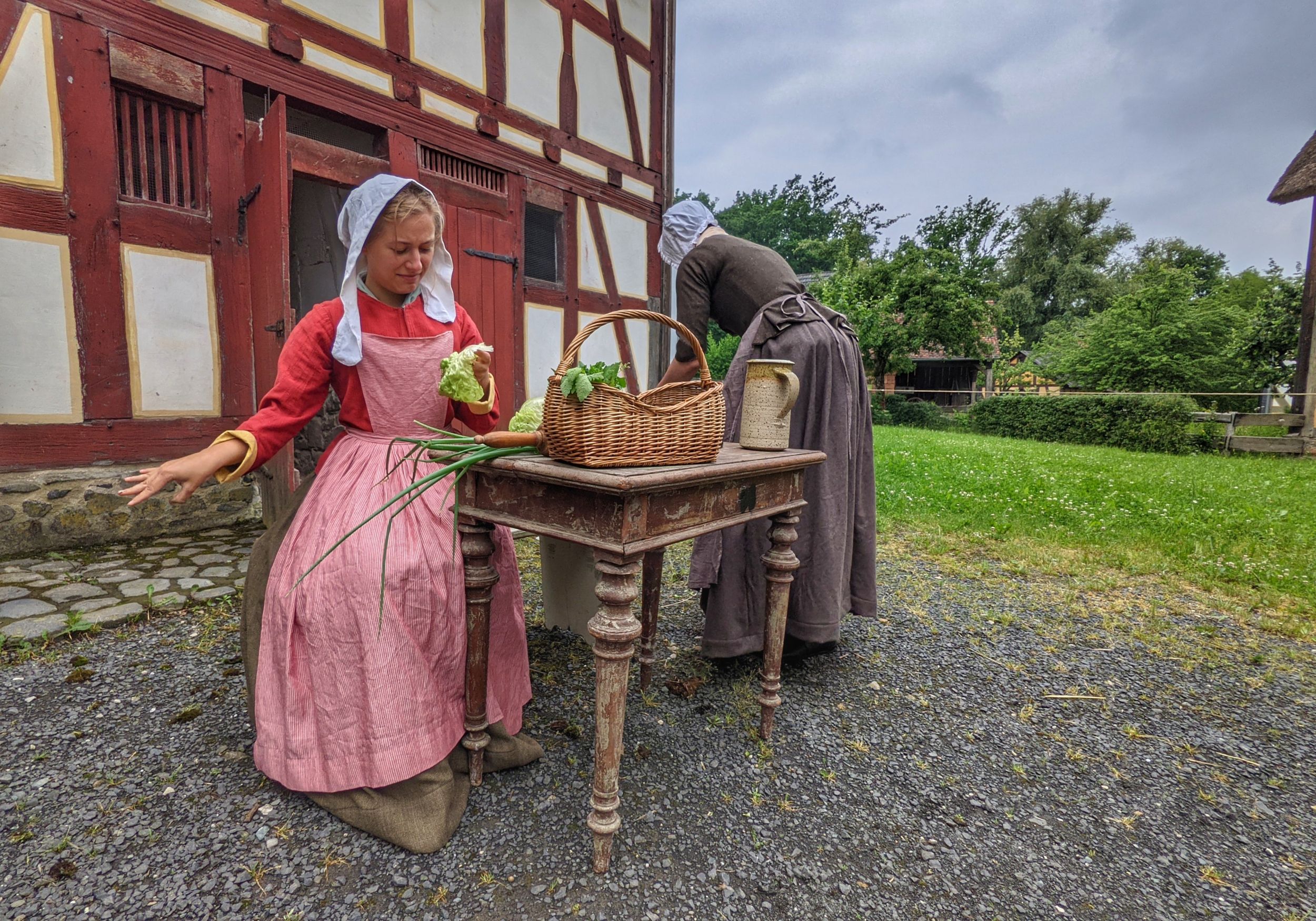 Szene aus dem Museumstheater: Zwei Bäuerinnen sitzen an einem Tisch und putzen Gemüse.