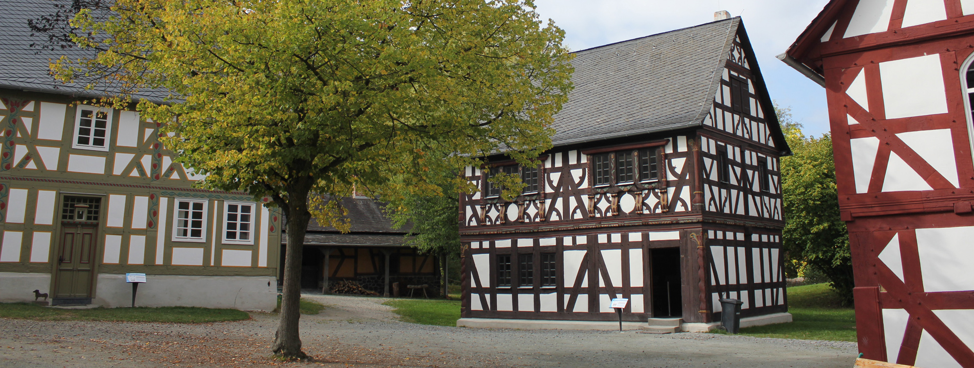 Außenansicht Haus aus Frickhofen. In der Mitte des Hofs ein großer Baum.