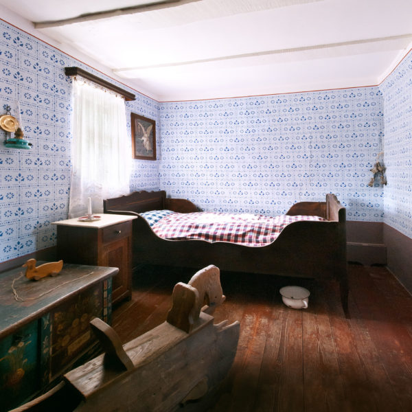 Kinderzimmer im Haus aus Fellingshausen mit Holzschaukelpferd, einer Truhe, einer kleinen Holzente und einem Bett