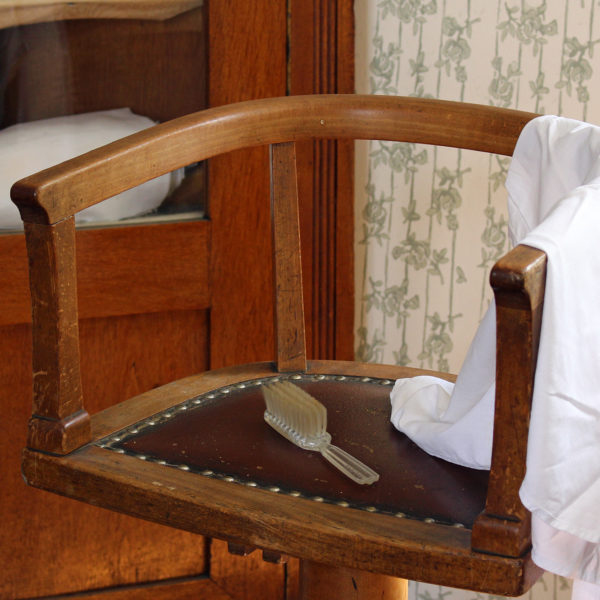 Haarbürste und Kittel auf einem historischen Frisierstuhl