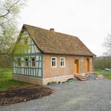 Das Altenteilerhaus aus Sieblos steht in der Baugruppe Osthessen. Die linke Seite ist eine Fachwerk-Fassade. An die Vorderseite wurden Holzschindeln angebracht.