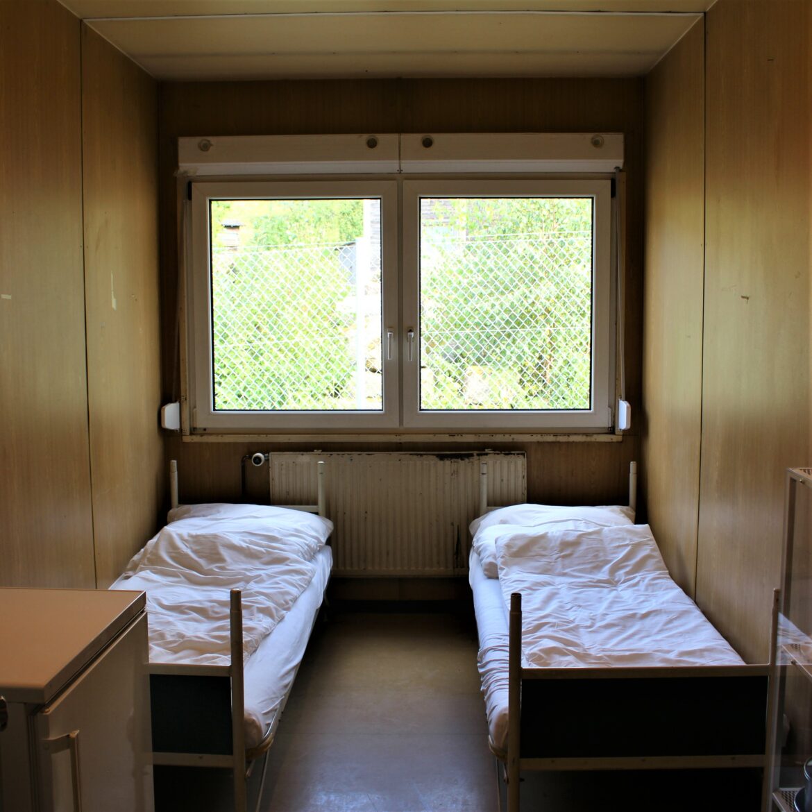 Karg eingerichtetes Zimmer aus dem Container für Geflüchtete mit zwei Betten und einem Tisch.
