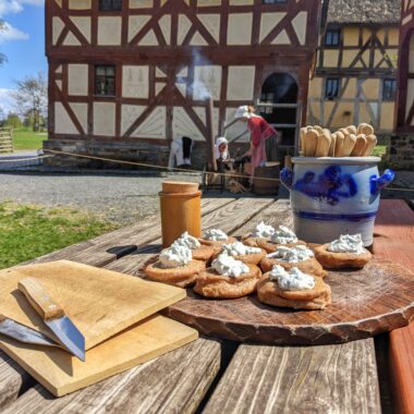 Schulprojekt "Kindheit auf dem Land", im Vordergrund sieht man eine Brotzeit, im Hintergrund zwei Bauersfrauen