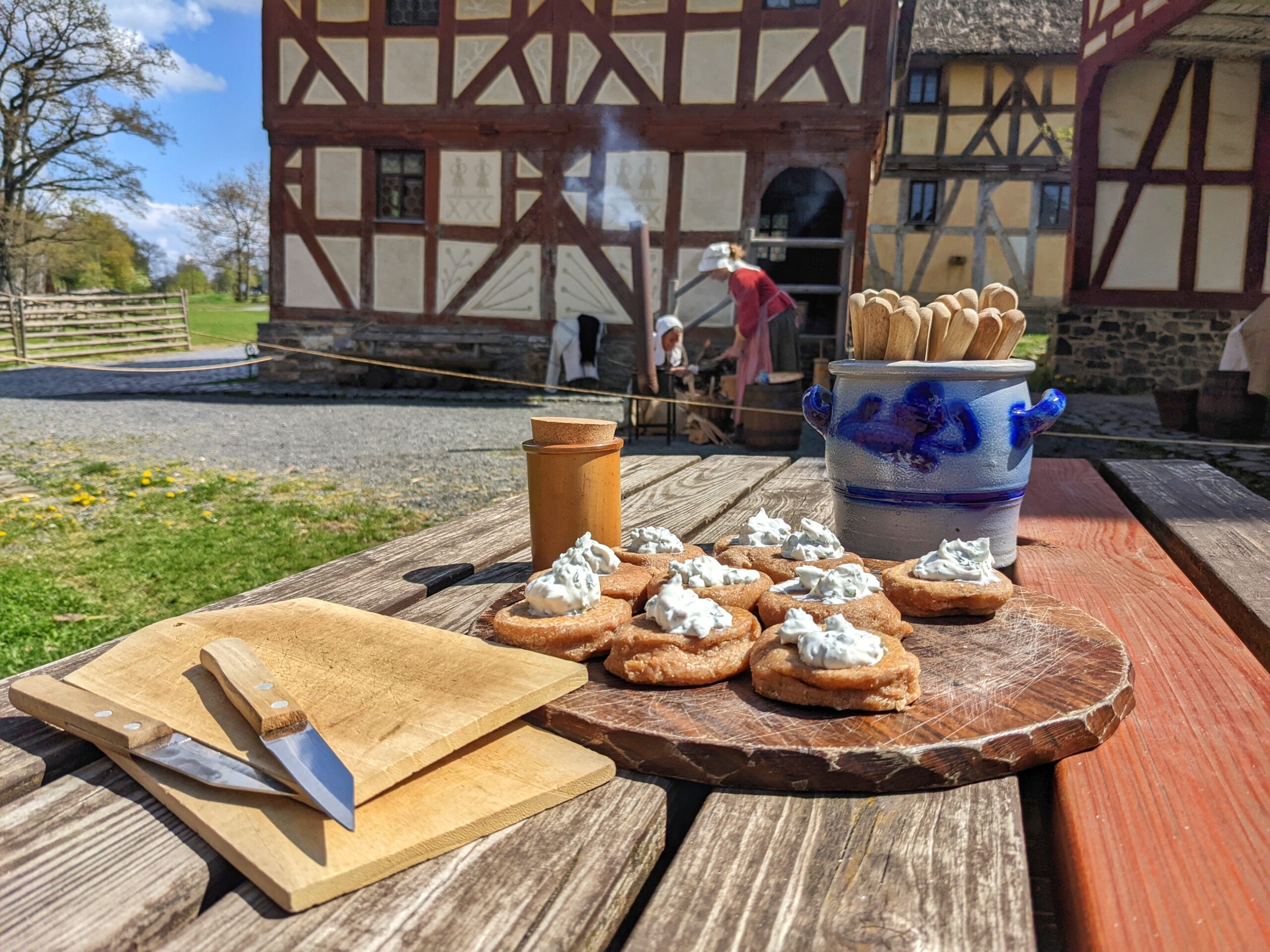 Schulprojekt "Kindheit auf dem Land", im Vordergrund sieht man eine Brotzeit, im Hintergrund zwei Bauersfrauen