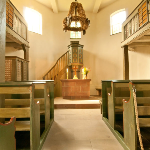 Gang zwischen den Sitzbänken in der Kirche aus Ederbringhausen mit Blick auf den Altar