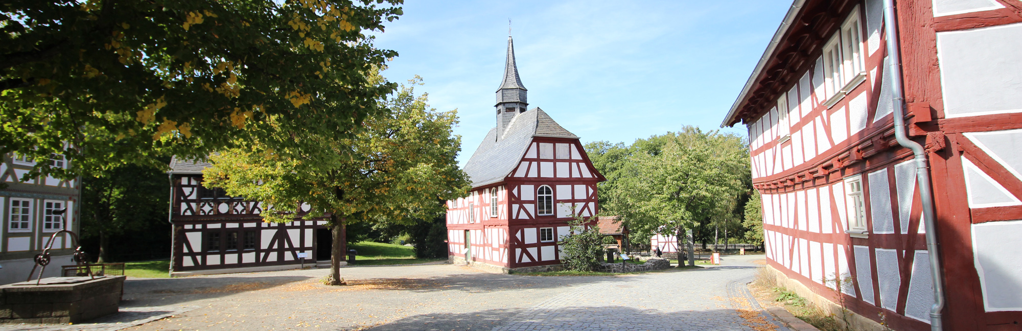 Fachwerkkirche am Dorfplatz mit Brunnen