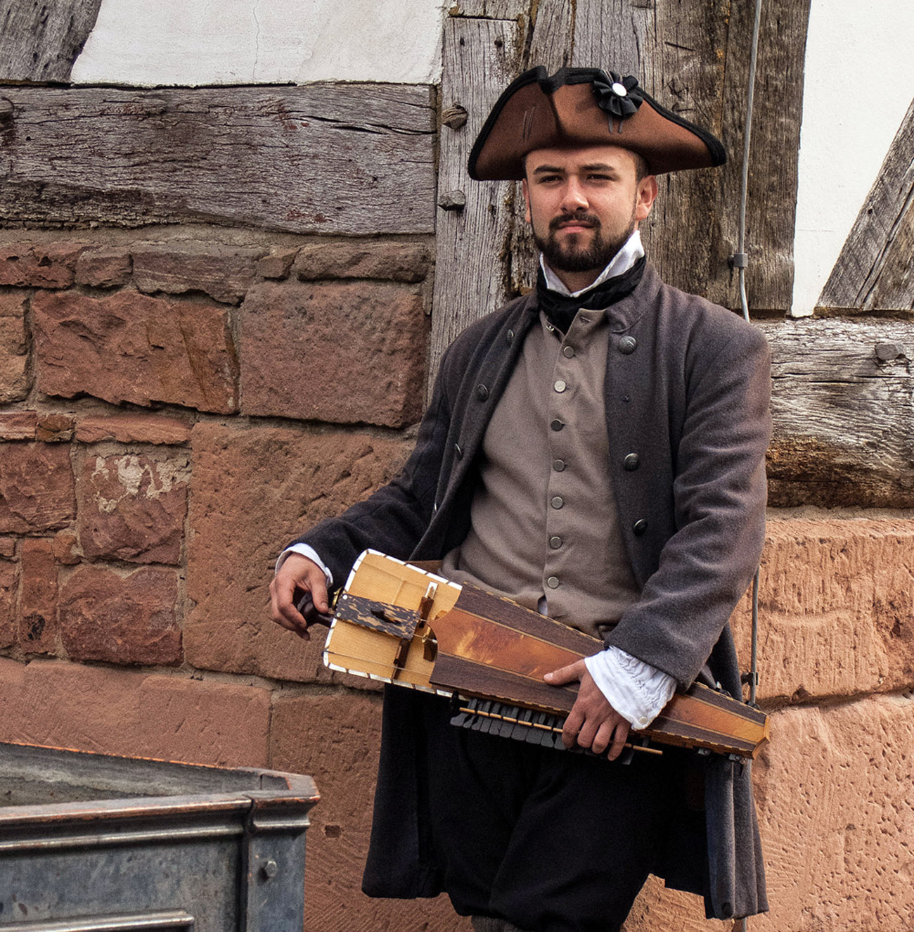 Schauspieler im historischen Kostüm spielt auf einer Drehleier
