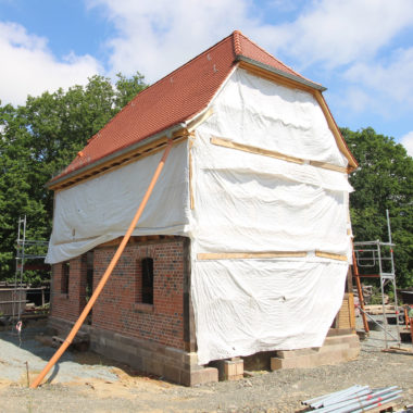 Fachwerkmusterhaus im Aufbau, abgedeckt mit einer weißen Plane