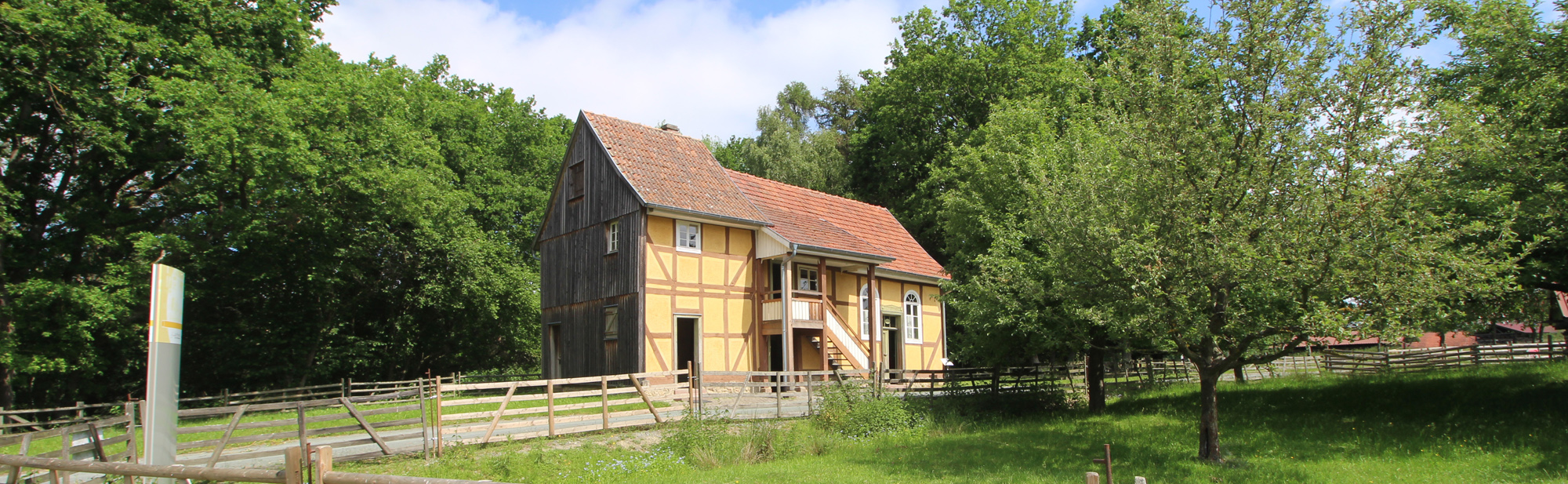 Die Synagoge aus Nentershausen steht zwischen einigen Laubbäumen am Wegesrand.