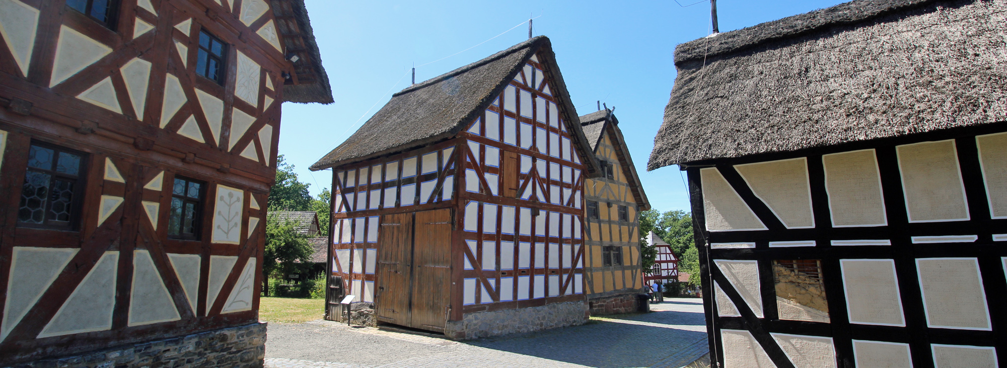 Fachwerkscheune aus Treusbach mit Holzbalken und weißem Gefache und Flügeltor als Scheuneneingang.