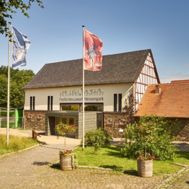 In der Scheune aus Westerfeld befindet sich der Museimseingang und die Kasse. Vom Parkplatz erreicht man das Gebäude mit wenigen Schritten. Ein gepflasterter Weg führt hinunter. An dessen Rand befinden sich zwei Fahnenmaste. Die Fahnen zeigen Handwerkerfiguren aus dem Hessenpark.