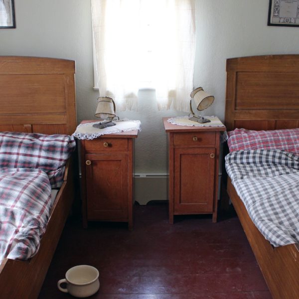 Schlafzimmer im Haus aus Eisemroth mit zwei Betten links und rechts an den Wänden. In der Mitte ein Fenster, darunter zwei kleine Nachttische.