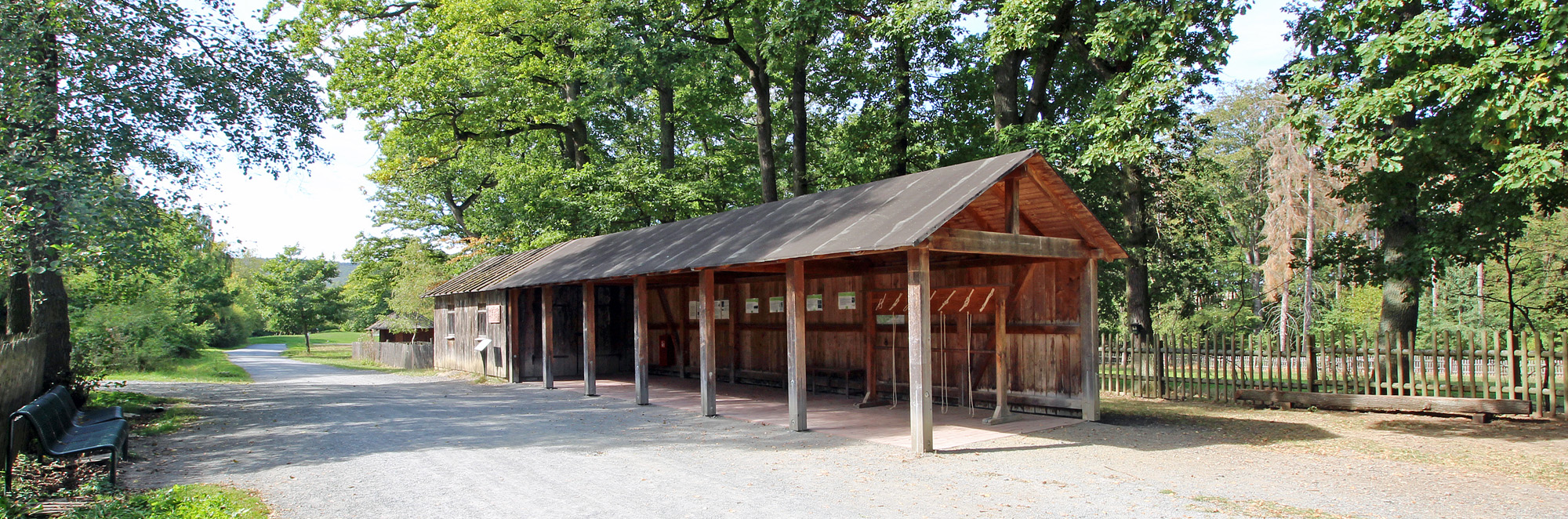Holzhütte mit offener Front und Dach auf geschottertem Untergrund
