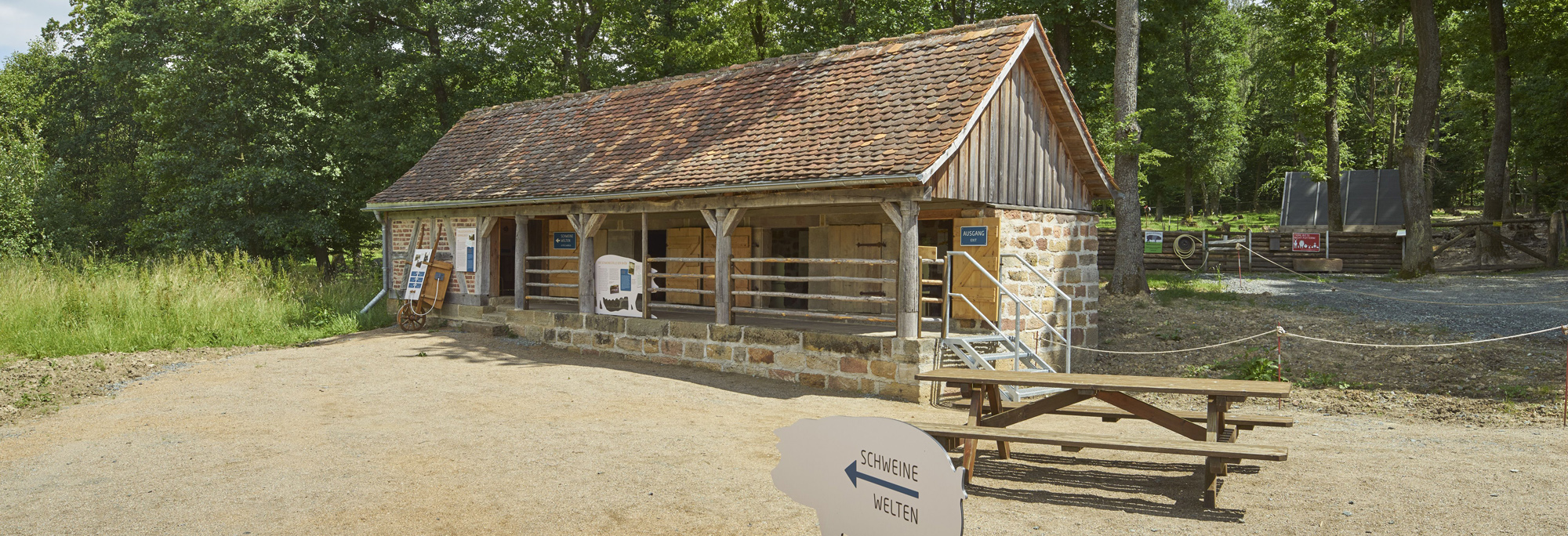 Außenaufnahme Stall aus Oberkalbach, im VOdergrund ein Aufsteller in Schweineform aus Holz