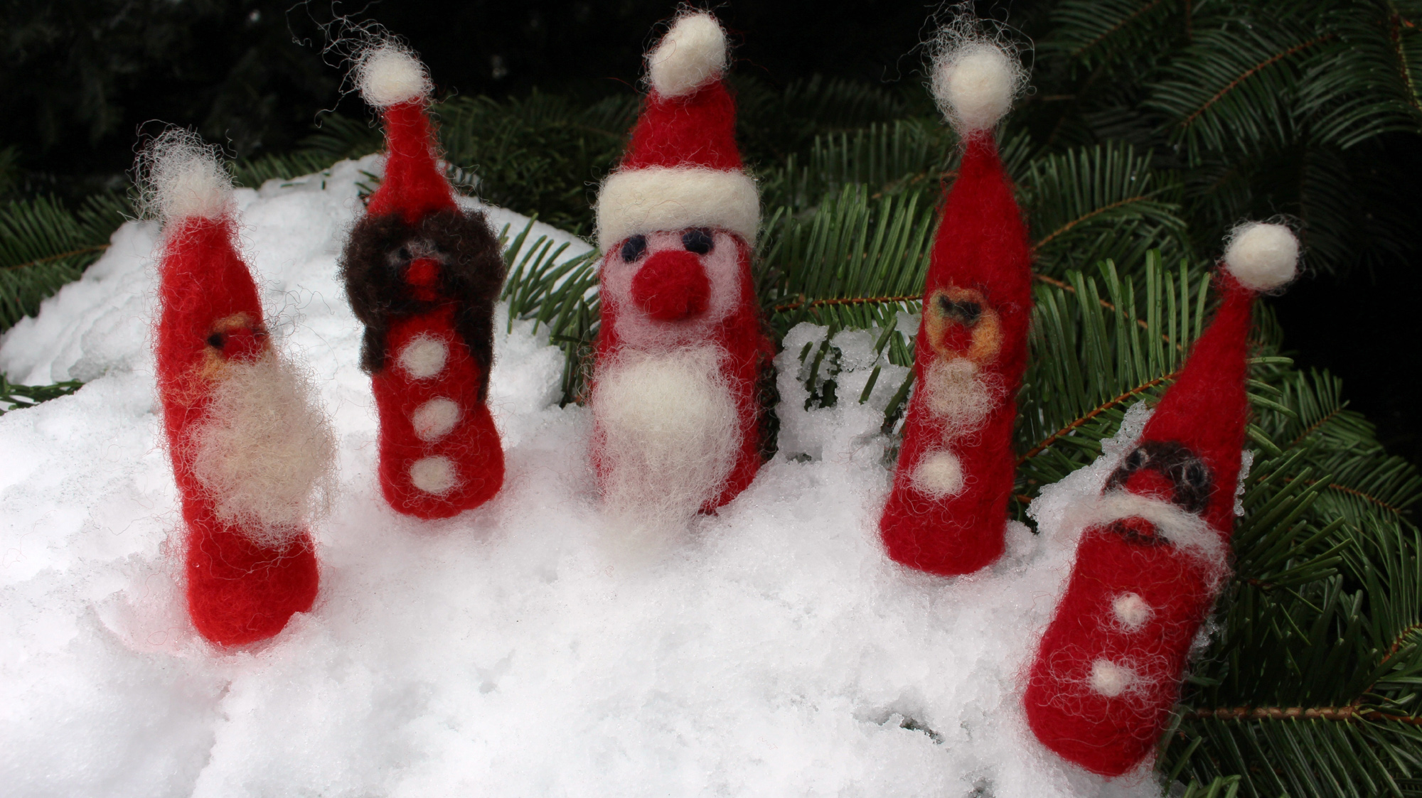 Gefilzte Nikoläuse stehen auf einer verschneiten Tanne