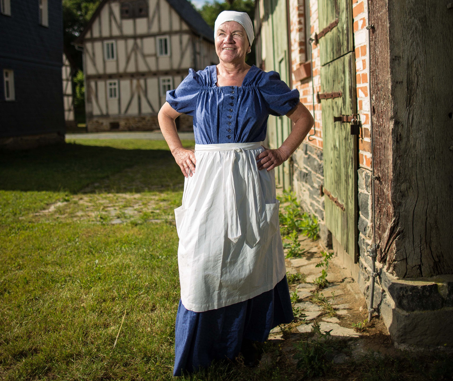 Historische Hausfrau in blauem Kleid mit weißer Schürze
